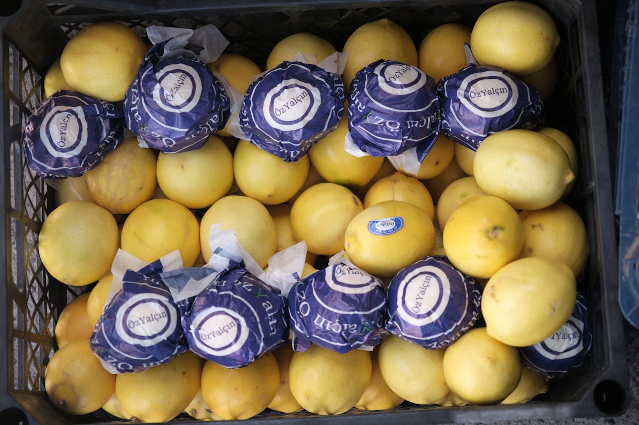 Top view of fresh lemons in a crate at a market. Some lemons are wrapped.
